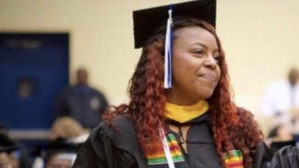 A woman standing in graduation regalia